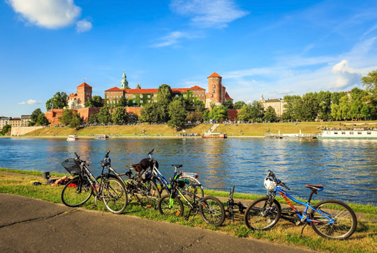 Bikes along a river with the Wawel castle in the backdrop